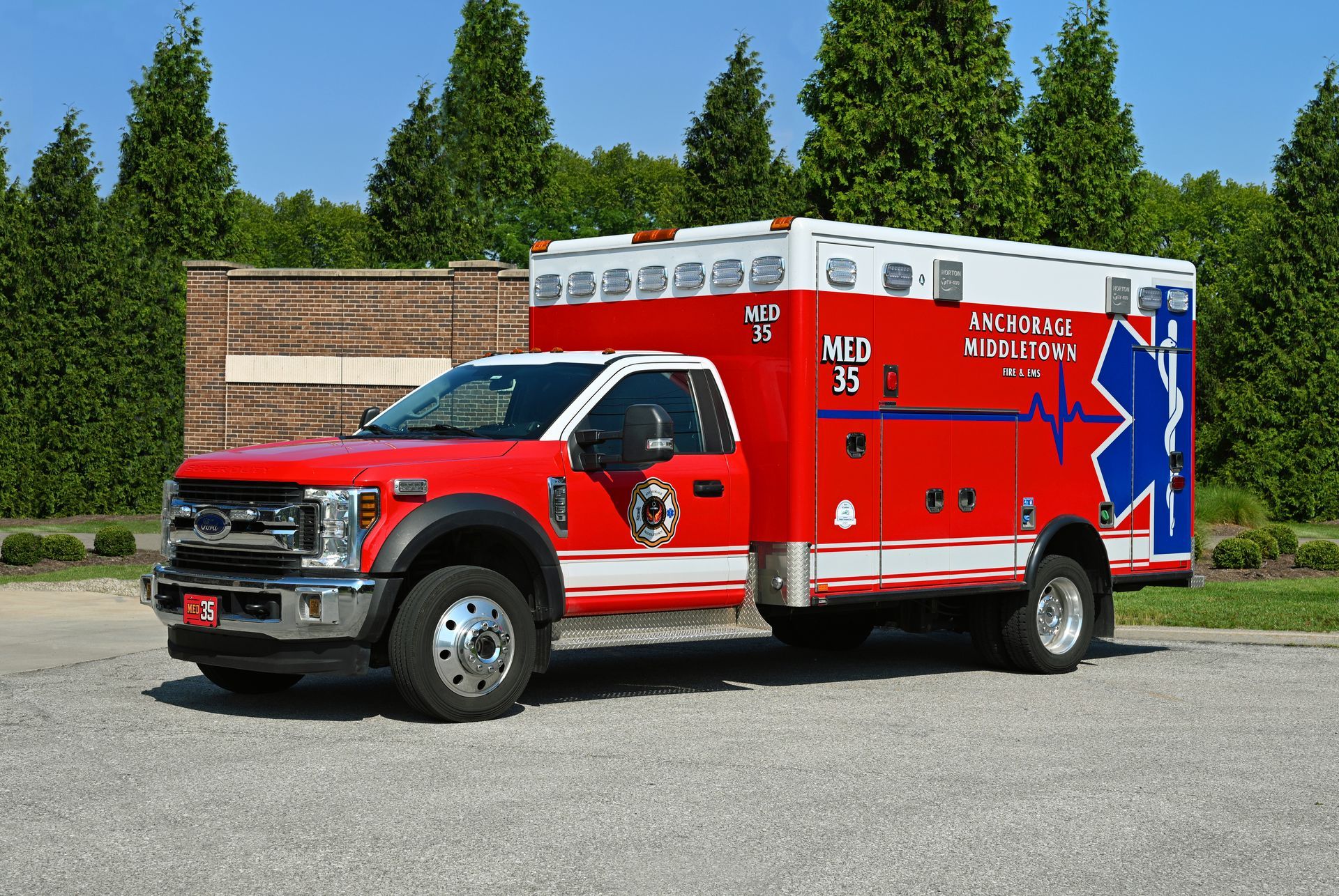 Red and white ambulance truck with blue star of life logo, parked outdoors.