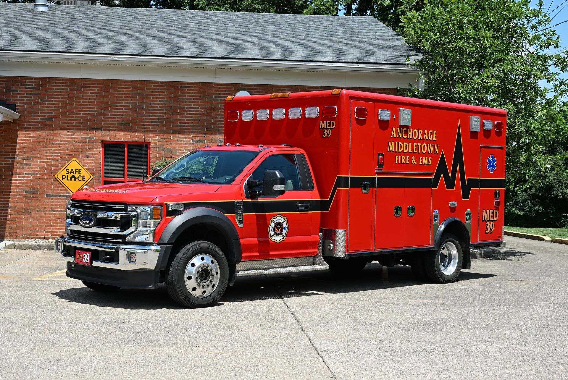Red ambulance parked in front of a brick building.