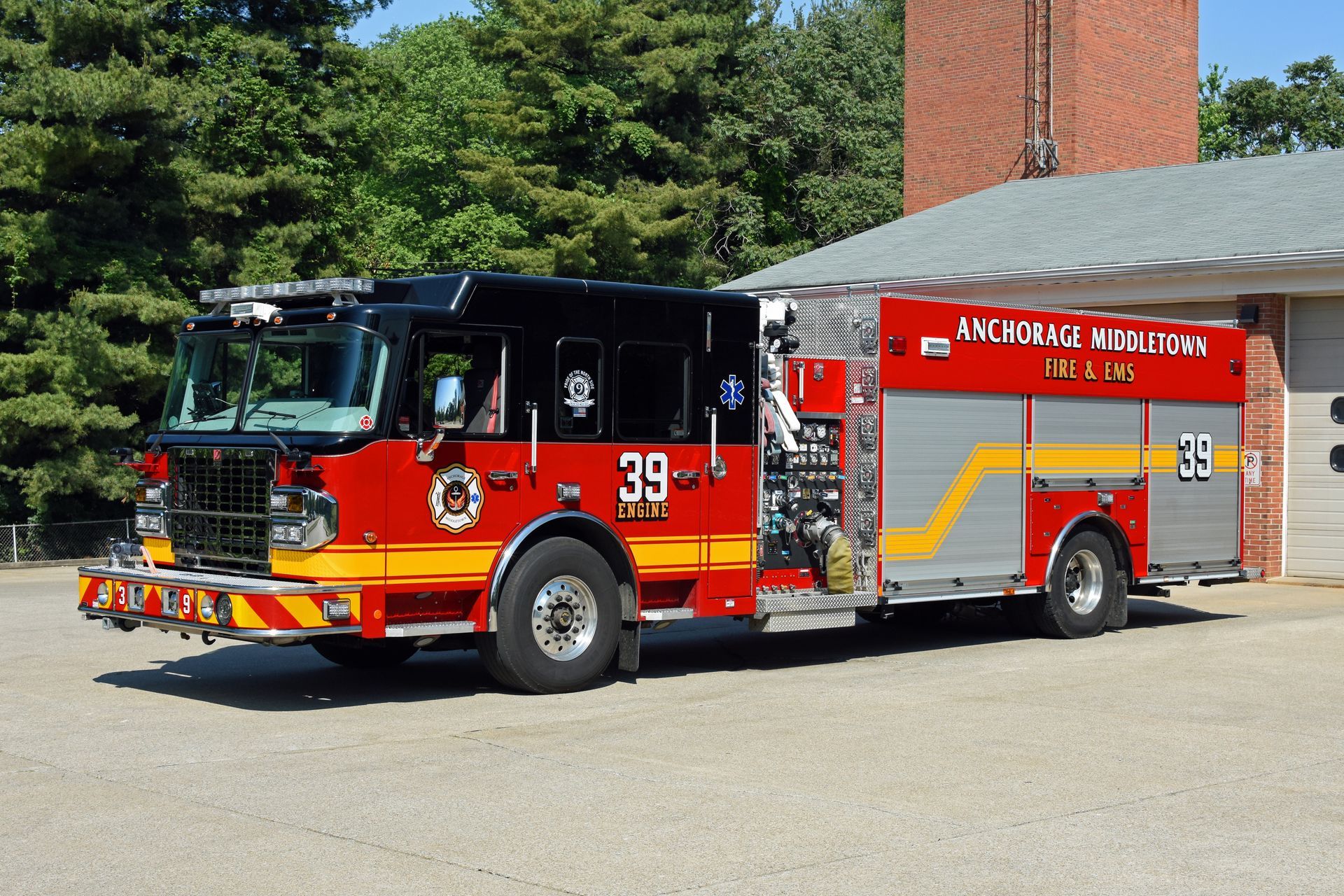 Fire truck, red and black, parked in front of a brick building. Truck has the number 39 on it.