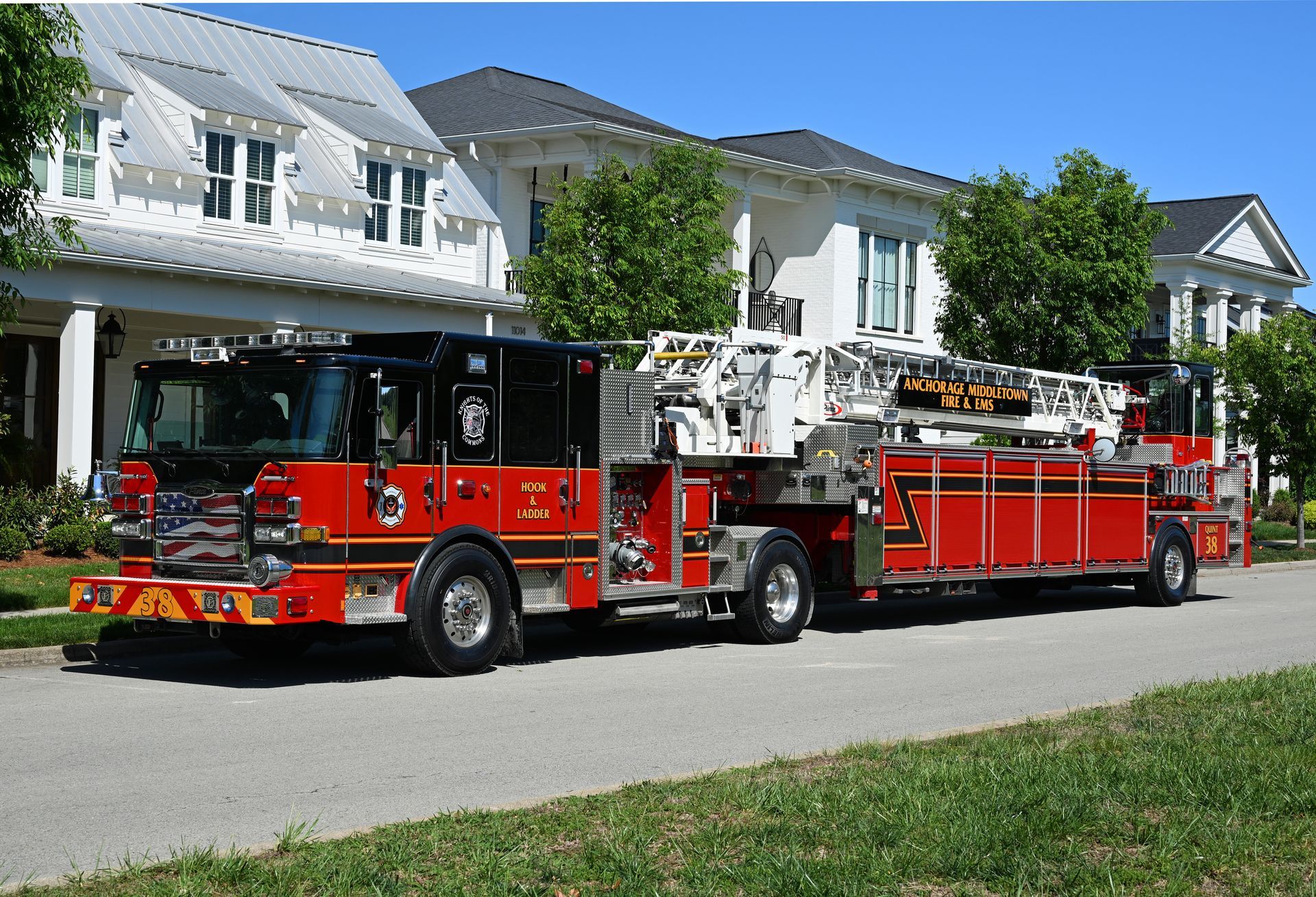 Red and Black fire truck with a hook & ladder, parked on asphalt with trees in the background. Anchorage Middletown Fire & EMS in Metro Louisville, Kentucky.
