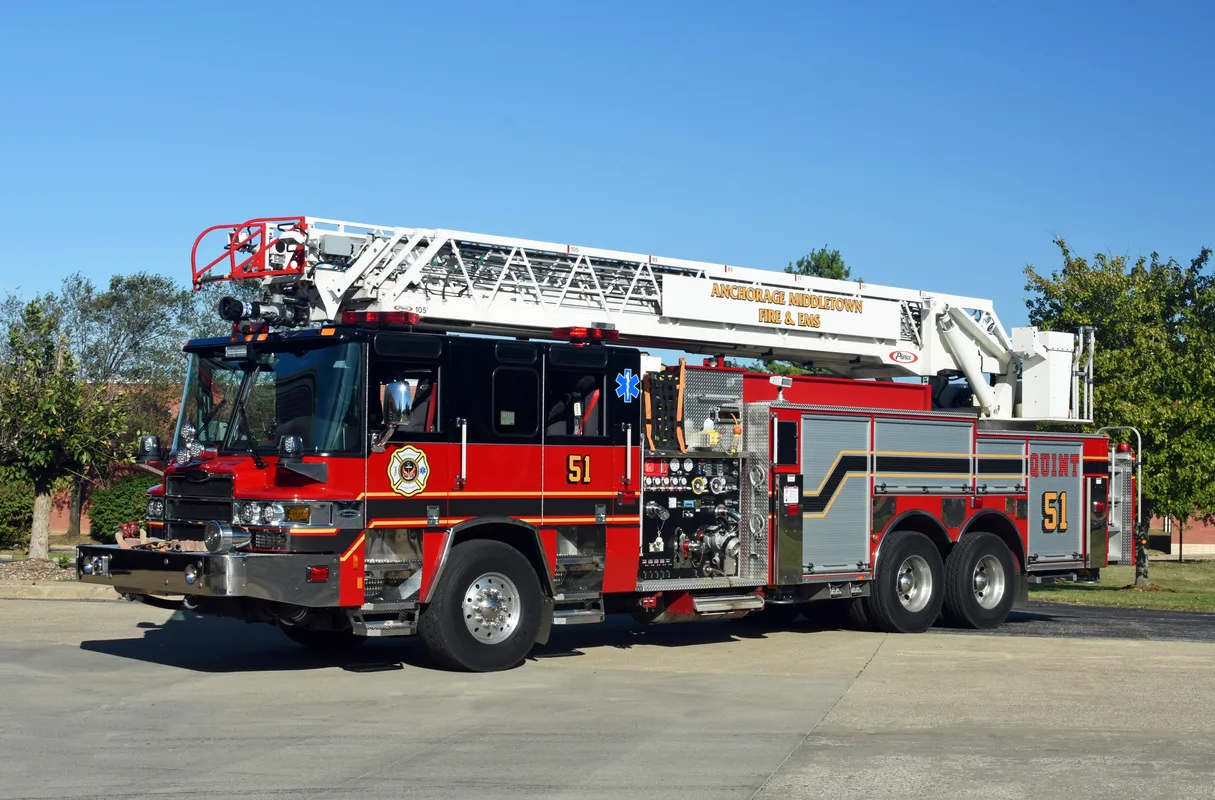 Red and silver fire truck with extended ladder, parked outside under a blue sky.