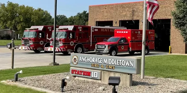 Fire station with red fire trucks parked outside, sign reads 