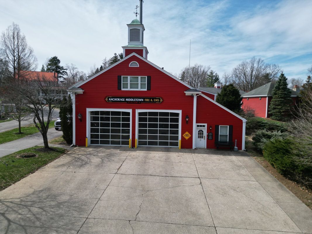 Red fire station with two garage doors, white trim, and a small tower.