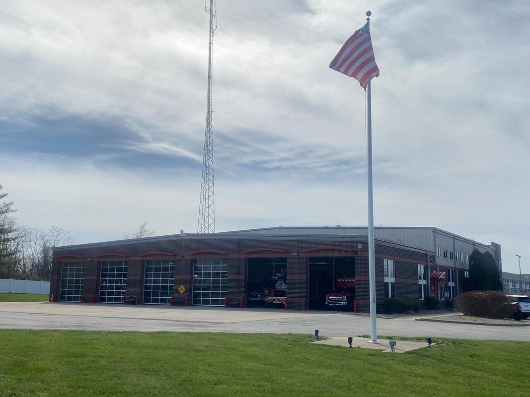 Fire station with open garage doors; American flag flies.