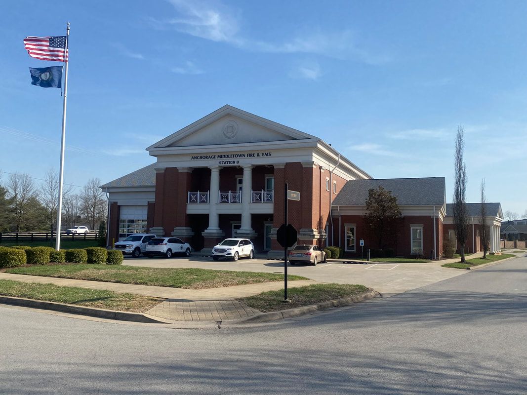 A brick building with white columns and a flag on a pole under a blue sky.