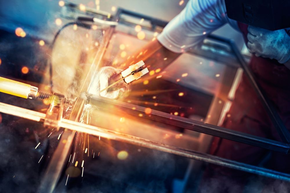 A Man Is Welding a Piece of Metal in A Factory — Magnum Steel In Crestwood, NSW
