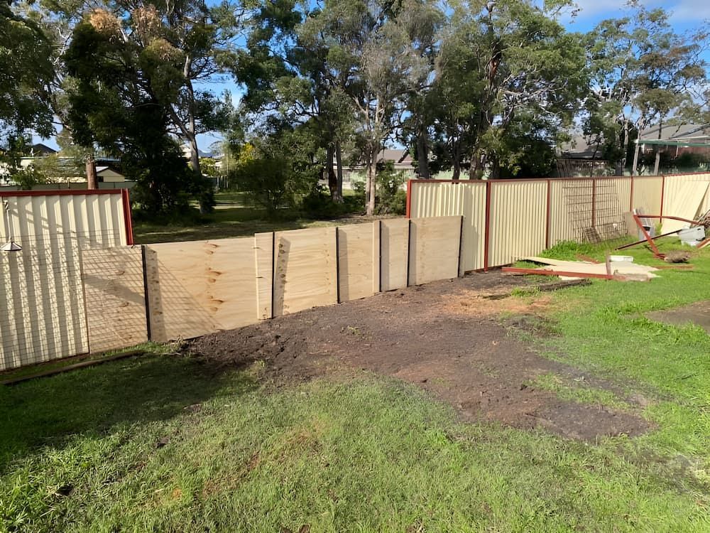 A Wooden Fence Is Surrounded By Grass And Trees In A Yard — All Area Tree Service Pty Ltd In Fountaindale, NSW