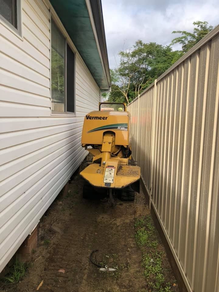 A Yellow Machine Is Parked On The Side Of A House Next To A Fence — All Area Tree Service Pty Ltd In Wyong, NSW