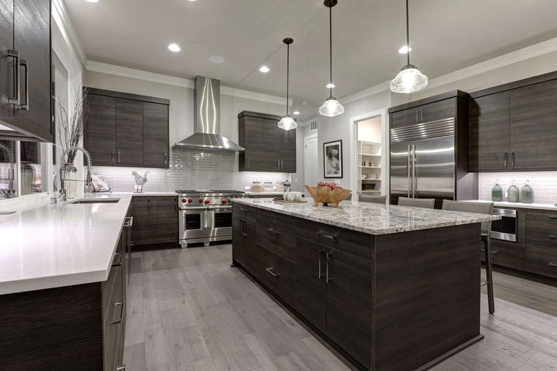 Modern kitchen with dark wood cabinetry, a large granite island, stainless steel appliances, and light gray flooring. Modern kitchen with dark wood cabinetry, a large granite island, stainless steel appliances, and light gray flooring.
