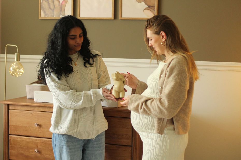 Twee vrouwen in truien bespreken een voorwerp in een sfeervol verlichte keuken.