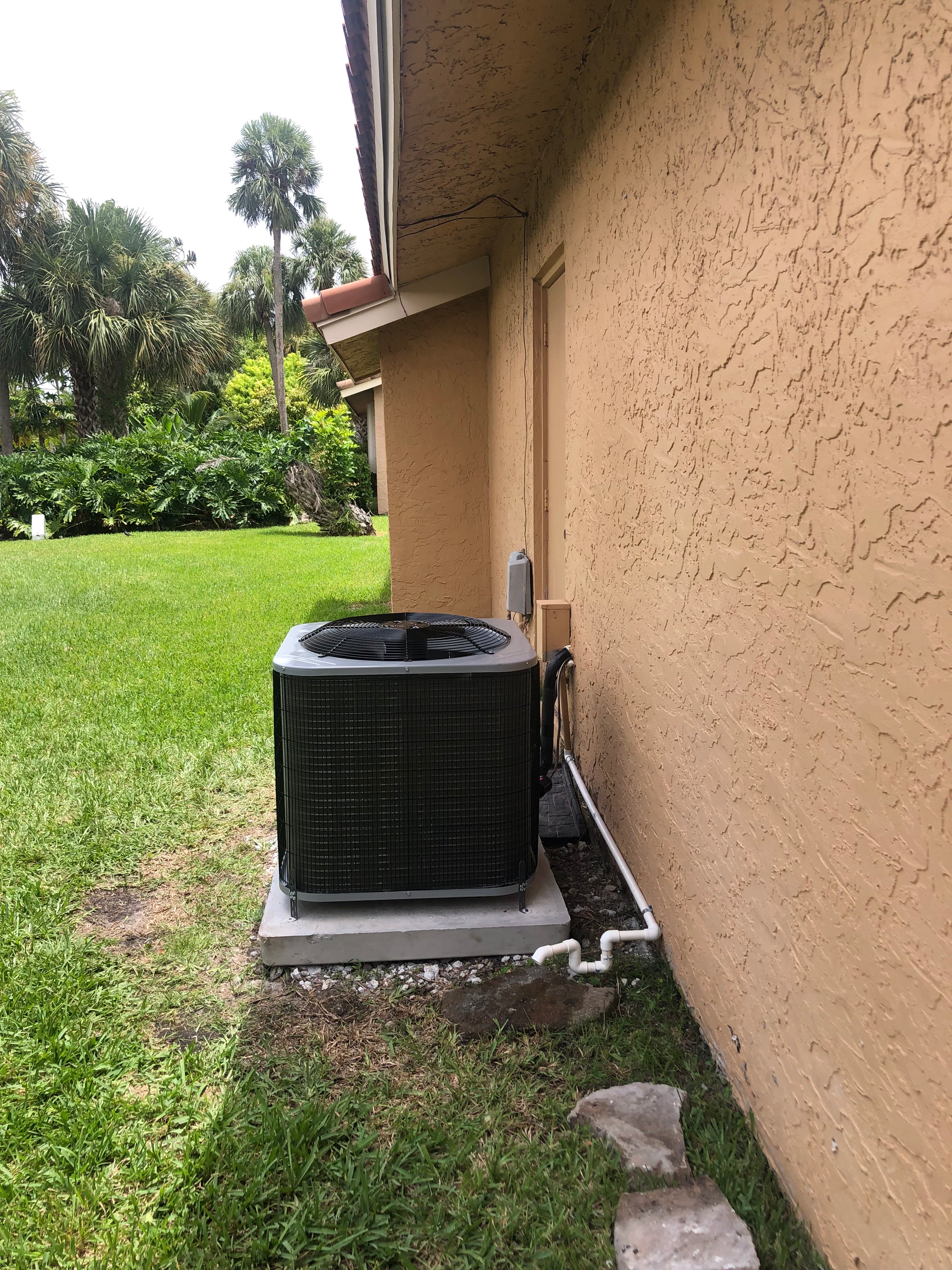 A black air conditioner is sitting on the side of a house.