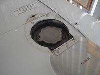 Close-up of an aircraft fuel cap on a white wing.