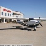 Airplane parked in front of Indy Aero building under a blue sky.