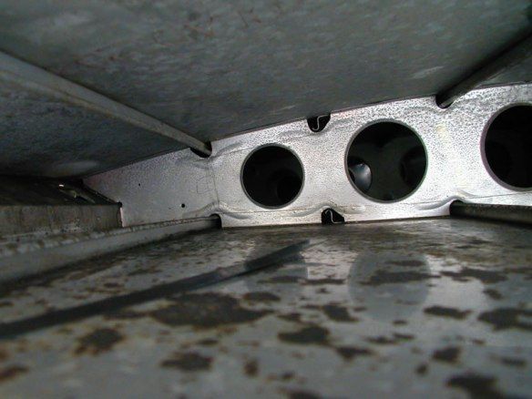 Inside view of metallic structure with several large circular holes and rivets.