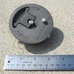 Circular gray valve with open/close indicator and a ruler beside it.