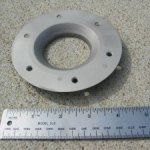 Silver metal circular flange with a central opening and six mounting holes, next to a ruler.