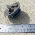 Metal drain plug with a blue rubber ring, next to a ruler.