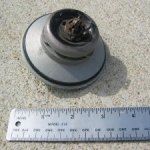 Metal object with a circular base, ruler for scale.