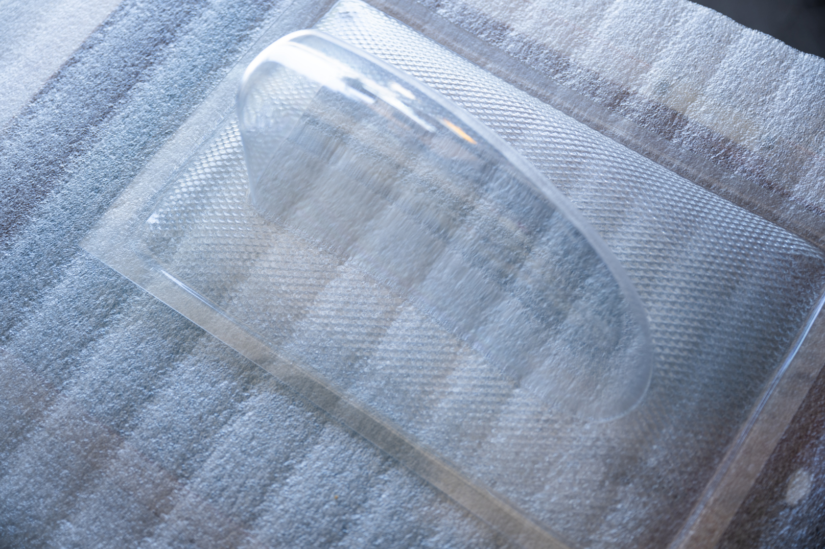Clear plastic lens, possibly for a vehicle's headlight or signal light, on a bed of protective foam.