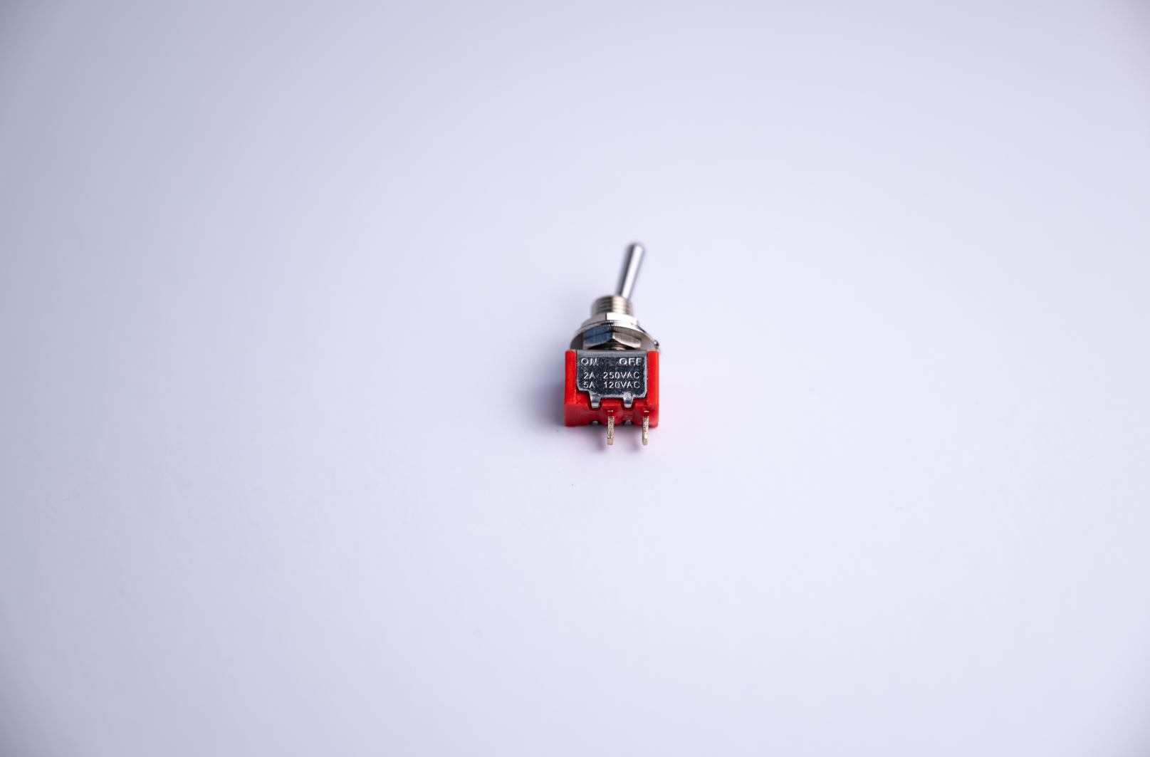 Red toggle switch with silver lever on a white surface.