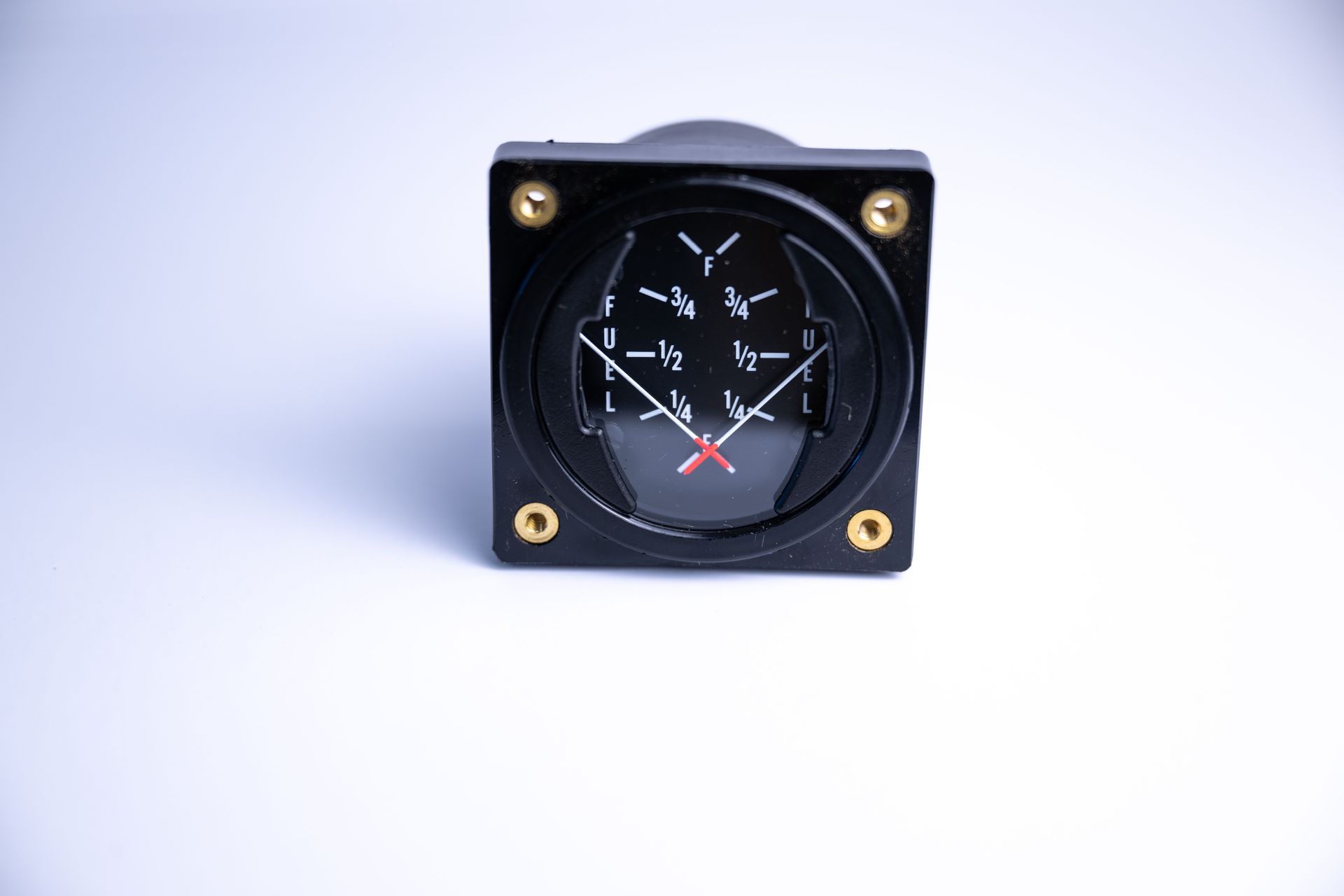 Aircraft turn coordinator gauge, black face with white markings and red needle, in a black case with gold screws.