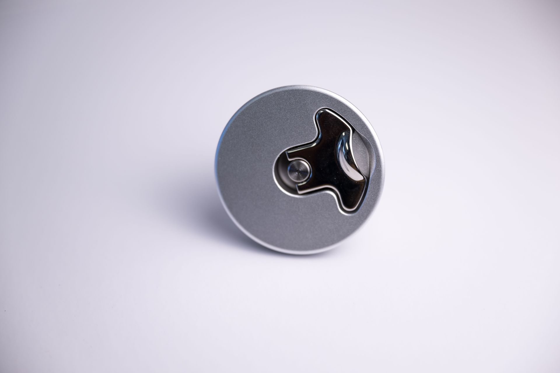 Silver and black round boat latch on a white surface.