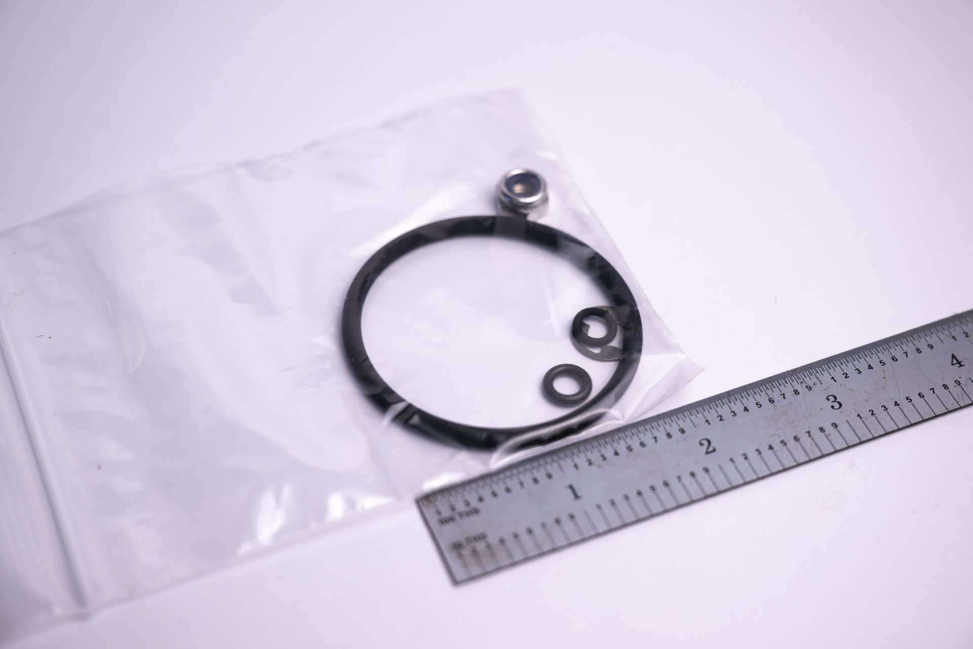 Bag containing an O-ring and other small hardware next to a ruler.