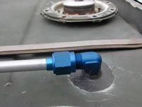 Blue fuel line elbow fitting attached to a fuel tank.