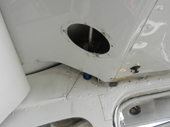 Inside of a white aircraft wing, a fuel tank access port is visible.