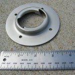 Silver metal circular flange with a central opening and three holes, next to a ruler.