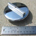 Chrome fuel cap with silver handle, shown next to a ruler.