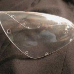 Clear plastic motorcycle helmet visor with several small holes.