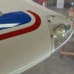Close-up of airplane wing tip with a headlight, white with red and blue stripes.
