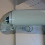 Light blue, cylindrical security camera mounted on a white wall.