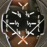 Fuel gauge with needle near empty. Reads: full, ¾, ½, ¼, and empty.