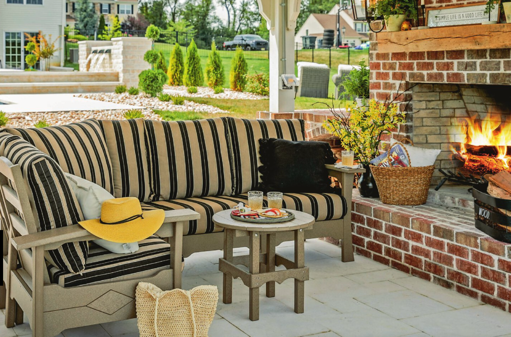 A showroom display with a light-colored outdoor sofa, fire pit, and dining set against a backdrop of siding samples.