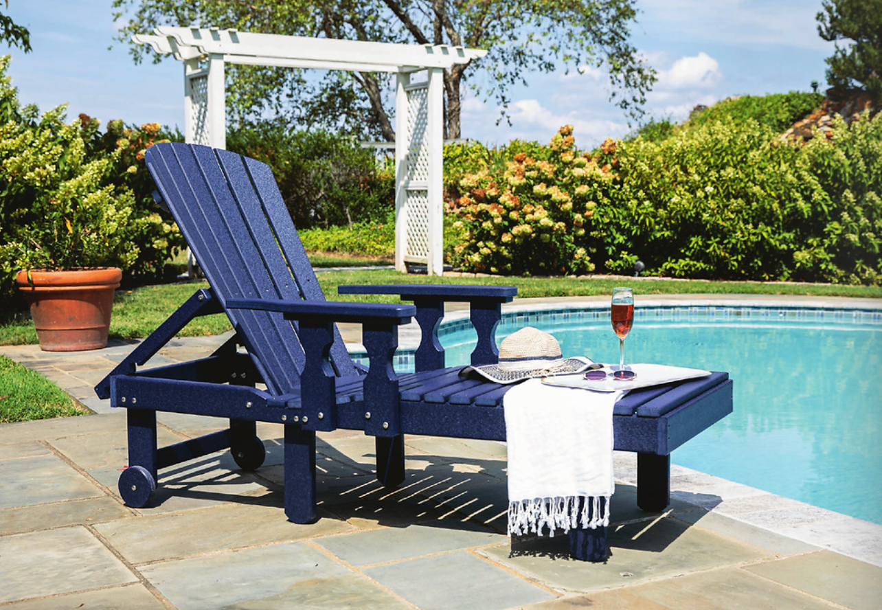 Covered patio dining set beside brick outdoor fireplace, with tableware and countryside view.