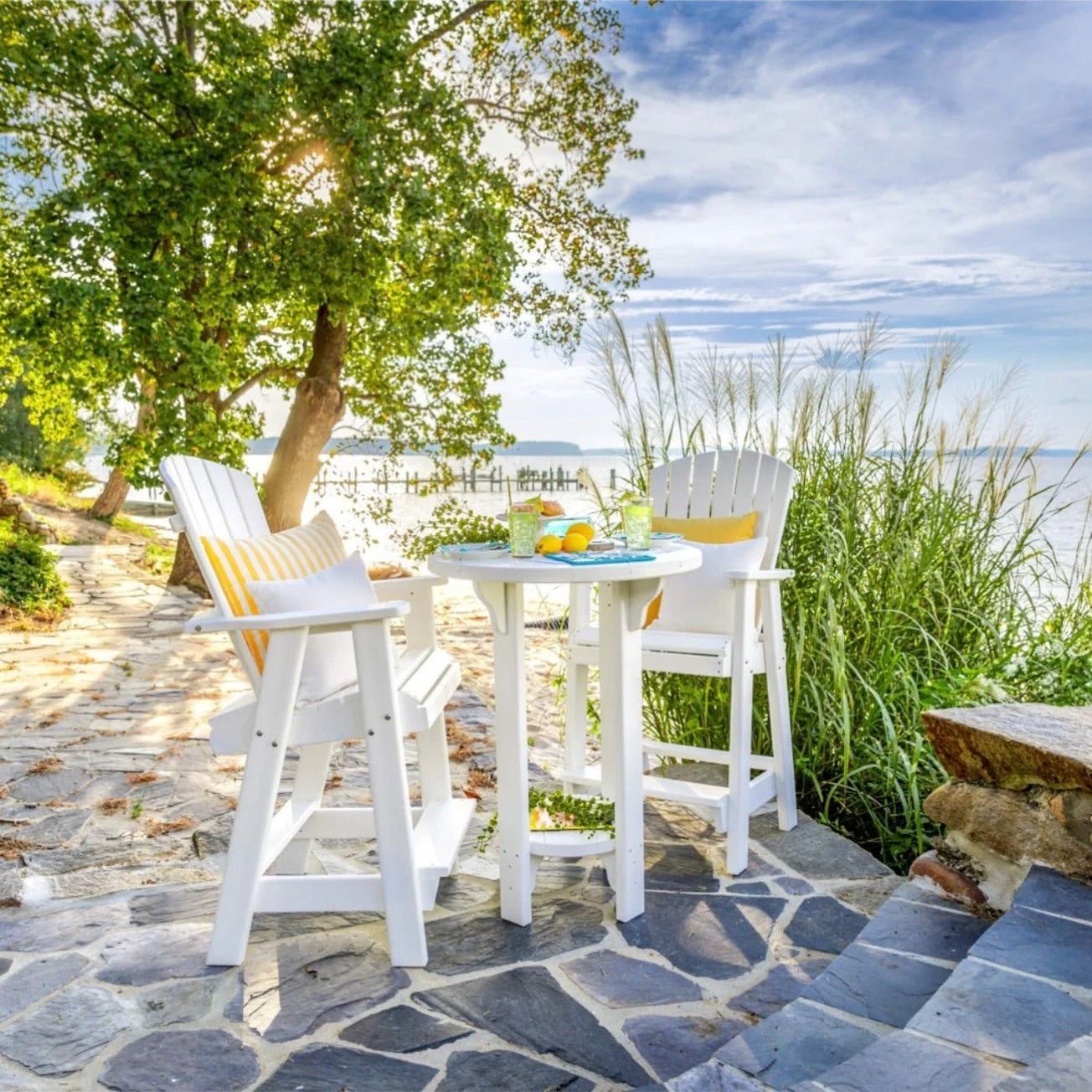 A patio features a bright green outdoor sofa, a dark wooden side table with potted plants, and a white, shingled wall.