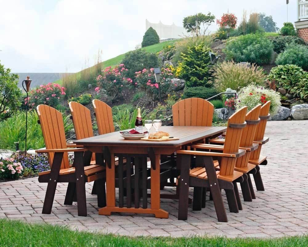 A light wood dining table set for four with woven placemats, dark plates, and a glass-enclosed tabletop fire pit.