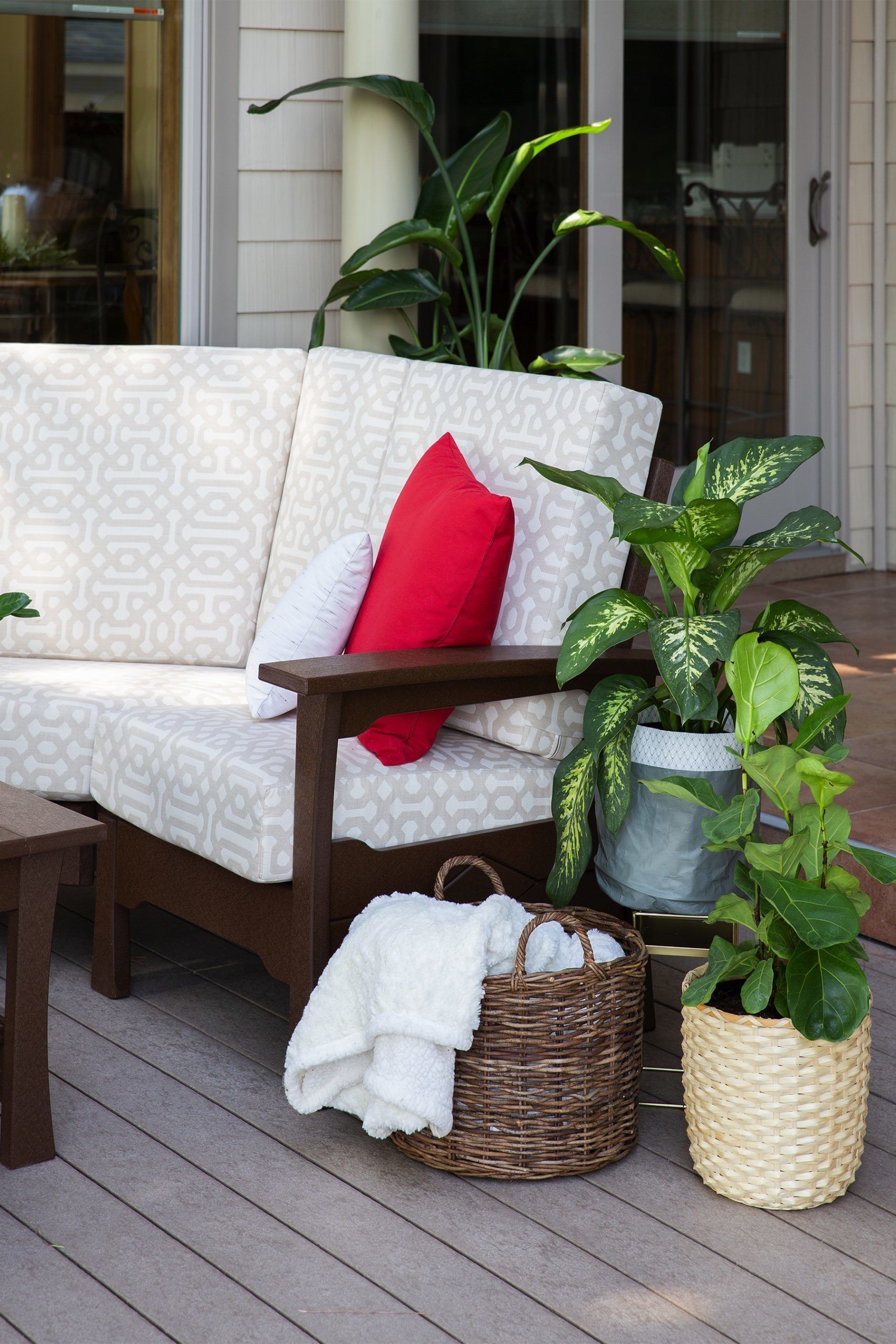 A light wood dining table set for four with woven placemats, dark plates, and a glass-enclosed tabletop fire pit.