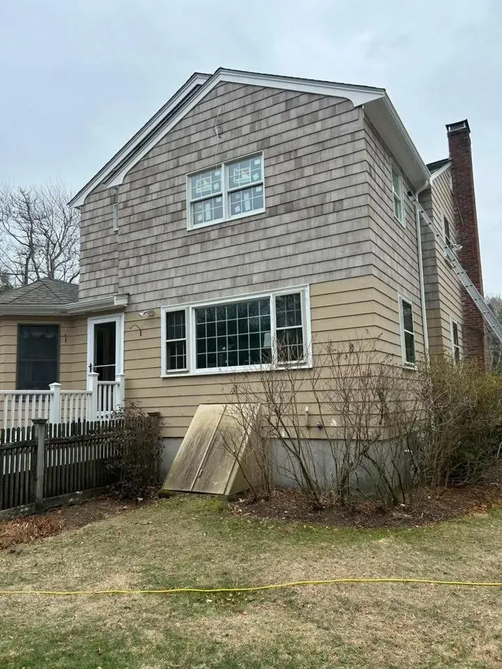 Two-story house exterior with gray shingle siding on top and tan horizontal siding on the lower half.