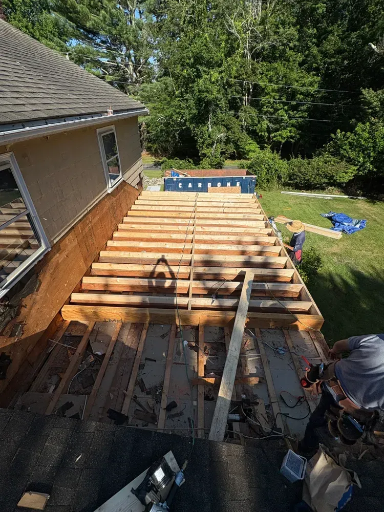 An elevated view shows a partially constructed wooden deck frame being built against the exterior wall of a house.