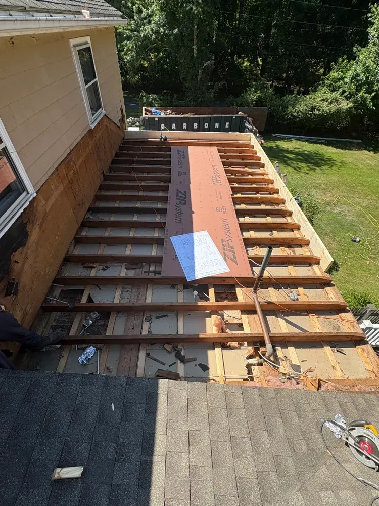 A residential roof under renovation showing exposed wooden framing and a single sheet of ZIP System sheathing.