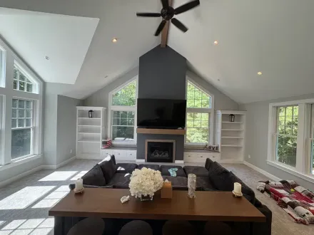 A cozy living room with a vaulted ceiling, dark grey fireplace wall, built-in shelving, and a large sectional sofa.