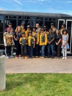 Group of people in yellow vests pose in front of a bus outdoors.
