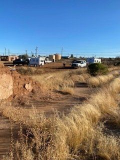 A rural scene with vehicles and trailers on dry land under a clear blue sky.