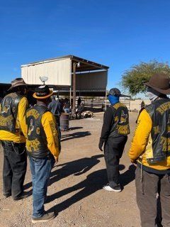 People in biker vests gathered outdoors near a building.