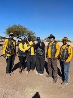 Group of people in yellow shirts and vests, holding a trophy outdoors.