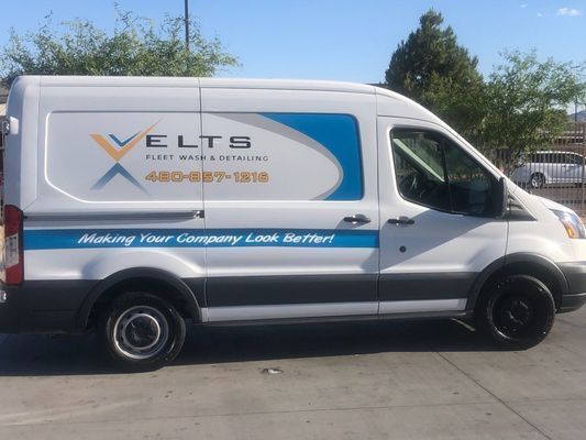White service van with blue and orange logo parked outdoors in a lot