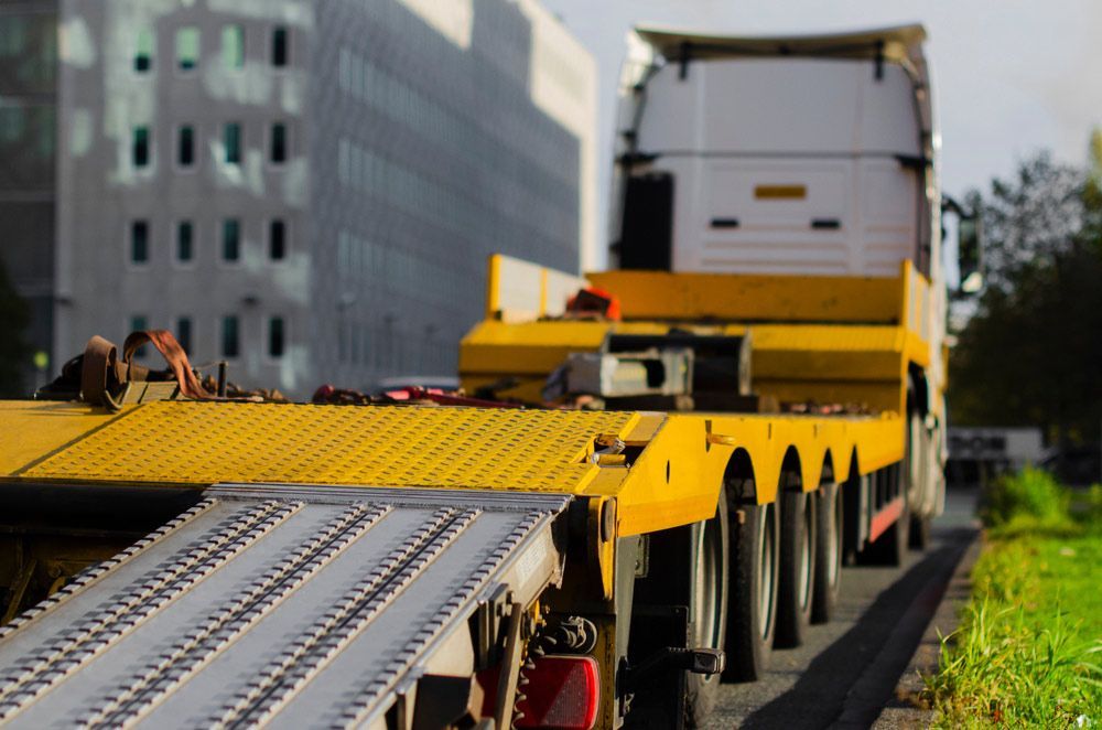 A Truck With A Trailer Attached To It Is Driving Down A Road — Gympie/Childers Towing Pty Ltd in Hervey Bay, QLD